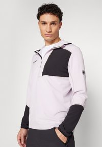 Μισό φλις μπουφάν με φερμουάρ σε ανοιχτό μοβ χρώμα με μαύρες λεπτομέρειες, που διαθέτει τσέπη με φερμουάρ στο στήθος, μακριά μανίκια και κουκούλα. Υφασμάτινη επιφάνεια.