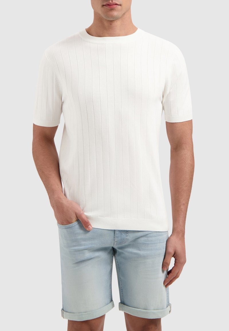Witte, kortlopende ribgebreide t-shirt met een ronde hals, gecombineerd met lichtblauwe denimshorts met omgeslagen zoom. Casual, getailleerde silhouette.