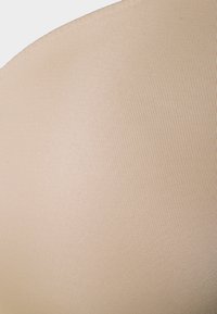 Tecido bege canelado com uma textura suave, apresentando uma forma ligeiramente curva, frequentemente usado para roupas íntimas ou lingerie.