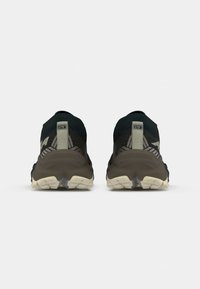 Black and olive green athletic shoes with a textured upper and cushioned sole. Features a tab at the back and a patterned design along the sides.