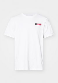 Camiseta de algodón blanca con cuello redondo, mangas cortas y un logo "Converse" en rojo y negro en el lado izquierdo del pecho.