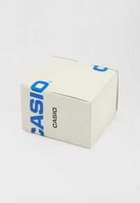 Caixa retangular branca da marca Casio com letras azuis e pretas sobre um fundo branco simples.