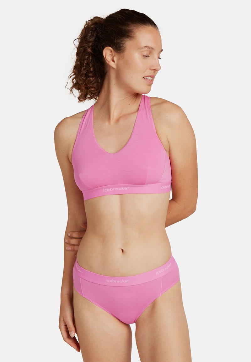 Vaaleanpunainen urheilBra ja hipster-alushousut, jotka on valmistettu pehmeästä kankaasta. Setissä on urheilullinen racerback-muotoilu ja joustava vyö, jossa on brändilogo.