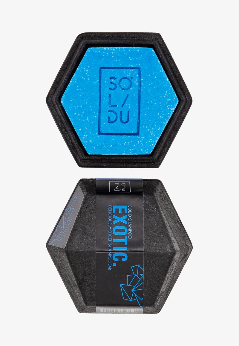 Festes Shampoo in hexagonaler Form, mit einem blauen Oberteil mit Sprenkeln und einem schwarzen Boden, etikettiert mit "EXOTIC" in Blau auf einer schwarzen Verpackung.