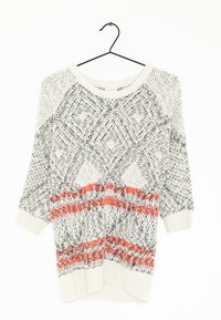 Sweter dzianinowy z geometrycznymi wzorami w czerni i bieli, z pomarańczowymi poziomymi paskami. Długie rękawy i szeroki dekolt. Wiszący na wieszaku.