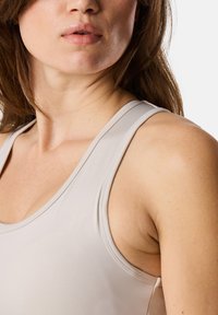 Débardeur gris clair en tissu lisse et extensible, avec de fines bretelles, un col rond et des détails de couture subtils près des bords.