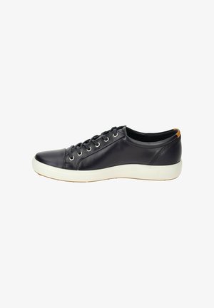 Zapatilla de cuero negro con perfil bajo, punta redonda, suela de goma blanca y seis ojales. Presenta un acento marrón en el talón.