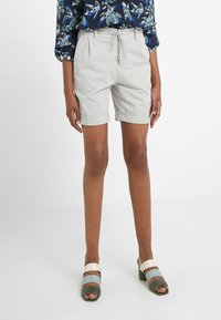 Ljust grå shorts med dragsko i midjan, uppvikta ärmslut och fickor, kombinerat med mångfärgade sandaler med breda remmar.