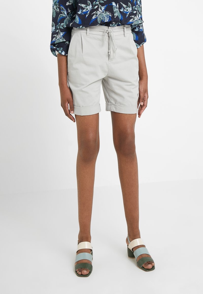 Ljust grå shorts med dragsko i midjan, uppvikta ärmslut och fickor, kombinerat med mångfärgade sandaler med breda remmar.