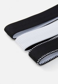 Tri elastične gumice za kosu: dvije crne i jedna bijela s teksturom i utorima. Crne gumice imaju glatke teksture, a jedna ima kontrastne šavove.