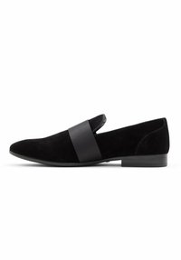 Black suede slip-on shoe featuring a wide satin band across the upper, rounded toe, and a low, textured heel for stability.