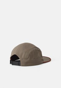 Brown cotton five-panel cap with black adjustable strap and dark brown edge on the brim, shown from the back on a white background.