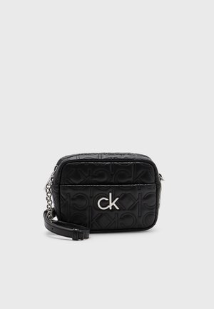 Schwarze rechteckige Umhängetasche mit geprägtem "ck"-Muster, silbernem "ck"-Logo auf der Vorderseite und Kettenriemen-Detail auf weißem Hintergrund.