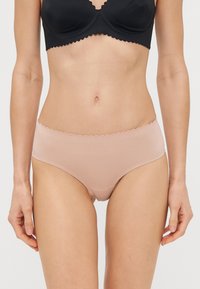 Bragas sin costuras de algodón de color nude, con bordes en el talle y las piernas en forma de ondas, que exhiben una textura suave y un diseño moderno de corte bajo.