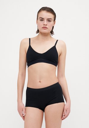 Crni pamučni set bralette i kratkih hlačica. Bralette ima tanke naramenice i široki pojas. Obje komponente imaju glatku teksturu i minimalno brendiranje.