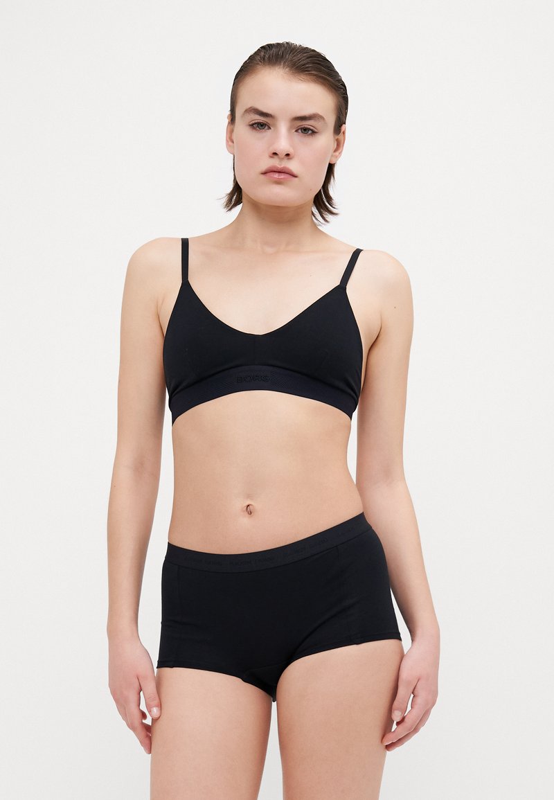 Fekete pamut bralette és shorts szett. A bralette vékony pántokkal és széles derékpánttal rendelkezik. Mindkét darab sima textúrájú és minimális márkázással ellátott.