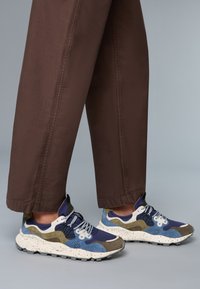 Baskets multicolores avec un mélange de marine, bleu, olive et semelle mouchetée blanche. Comprend des couches de suède, de matériaux en mesh et un design à lacets.