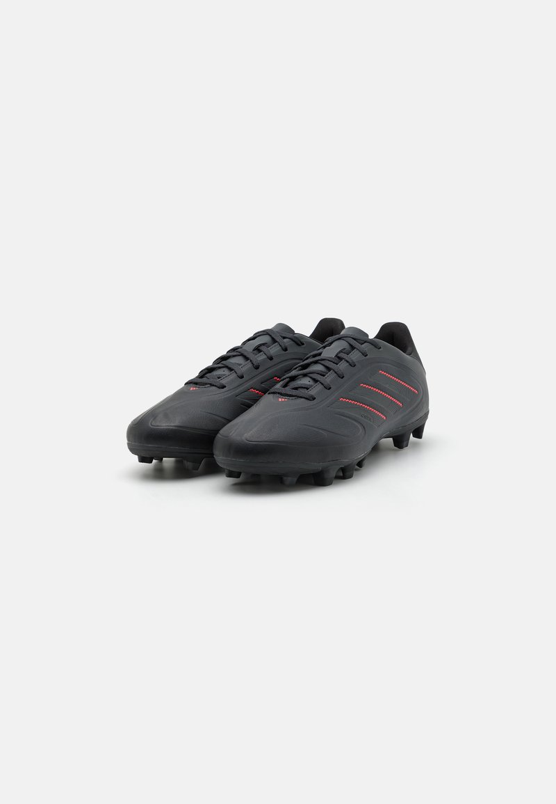 Botas de fútbol negras con parte superior sintética texturizada, que cuentan con tres franjas rojas, cierre de cordones y tacos moldeados para tracción.