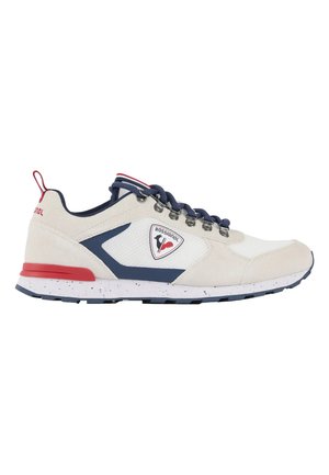 Weißer und marineblauer Rossignol-Sneaker mit roten Akzenten, Schnürverschluss und Logopatch an der Seite, seitlich dargestellt.