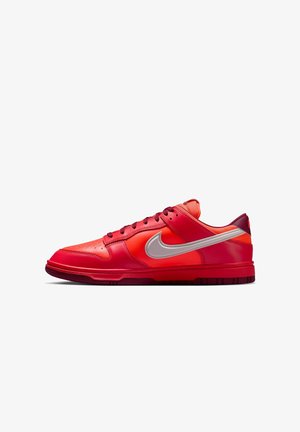 Czerwono-pomarańczowe sneakersy Nike z błyszczącą skórzaną cholewką, wyraźnym srebrnym znakiem Swoosh i teksturowaną gumową podeszwą z głębokimi rowkami.