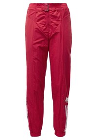 Červené teplákové kalhoty s elastickými kotníky, bočními bílými pruhy, předním zipem a detailem přezky na pase.