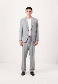 Light gray striped suit with two-button blazer and tailored trousers. Worn over a white shirt, paired with black shoes. Smooth fabric texture.