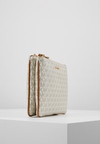 Beige mønstret håndtaske med guldfarvet hardware, der har lynlås og brune læderdetaljer, rektangulær form med et struktureret design.