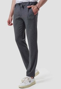 Men's dark gray sweatpants in soft fabric, featuring a drawstring waist, side pockets, and a straight leg design, paired with white sneakers.