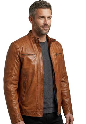 Mann mit kurzem grauem Haar und Bart, trägt eine braune Lederjacke über einem dunkelgrauen Pullover, blickt leicht nach rechts, neutraler Gesichtsausdruck.