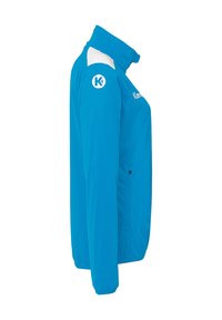 Blå sportsjakke med høj krave, hvide detaljer på skuldrene, lynlåslommer i siderne samt branding på brystet og armen.