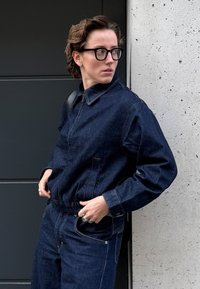 Tumesinises toonis teksatagi ja sobivad püksid, millel on lukk, krae ja elastsest vöökohast. Riietel on peen tekstuur.