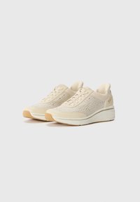 Beige knitted sneakers with a textured upper, subtle shimmer, and a cushioned white midsole. Features lightweight construction and lace closure.