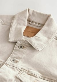 Beige denim shirt met een klassieke kraag, knoopsluiting en leren label. Zachte textuur met zichtbare stiksels en metalen knopen.