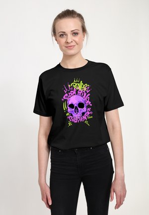 Sort t-shirt med et grafisk design af et skelet i lilla og grøn med markante detaljer, sat mod en ensfarvet baggrund.