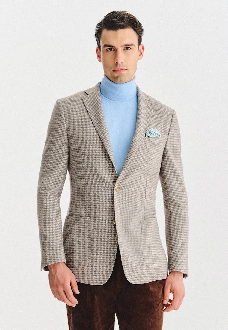 Męska marynarka w jasnobrązowy wzór houndstooth, z klapami, dwoma przednimi kieszeniami i brązowymi spodniami z kordurowej tkaniny. Jasnoniebieski golf pod spodem.