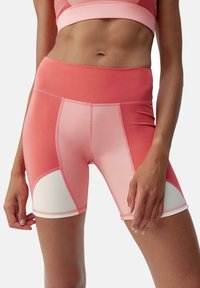 Hooggeresimde fietsbroek in tinten van roze, met contrasterende witte panelen, gemaakt van soepel elastisch materiaal en vlakke naden voor comfort.