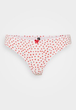 Katoenen string in het wit met een rood en zwart hartpatroon. Voorzien van een klein rood strikje aan de voorkant. Zachte textuur met een comfortabele pasvorm.