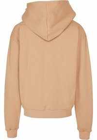 Hettegensere i lys beige, med en avslappet passform, ribbestrikkede mansjetter og kant. Glatt bomullsmateriale med en ensfarget bakside.
