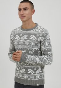 Grå strikket sweater med indviklede hvide geometriske og snefnugs mønstre, ribbede manchetter og rund hals.