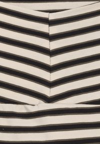 Sort og hvid stribet stof med et chevronmønster, der har en ribbet struktur. Striberne er jævnt fordelt og varierer i bredde.