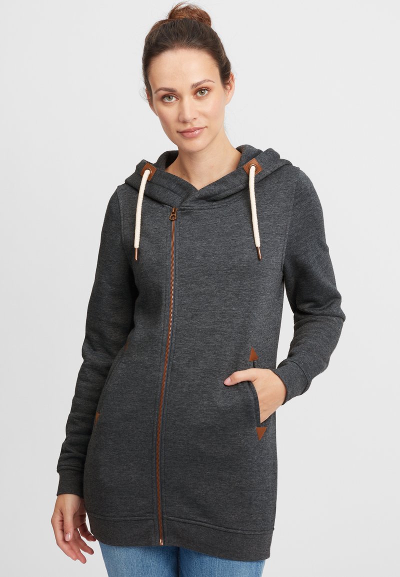 Kolgrå hoodie med dragkedja fram, dragsko på huvan och bruna detaljer. Har fickor med triangulära detaljer, tillverkad av mjukt tyg.