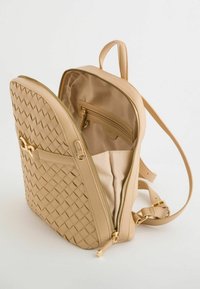 Sac à dos en cuir tissé beige avec quincaillerie dorée, fermeture zippée sur le dessus, et un compartiment intérieur comprenant une poche et une doublure en tissu.
