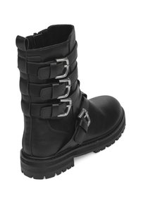Bota de tobillo de cuero negro con tres correas ajustables y hebillas de plata, punta redondeada y suela de perfil rugoso para un buen agarre.