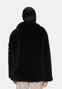 Cappotto in finta pelliccia nera con un grande colletto, vestibilità morbida e maniche lunghe. Presenta una texture morbida e un design senza cuciture senza chiusure visibili.