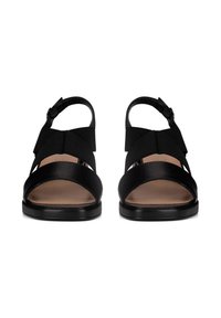 Sandalias negras con un diseño de tiras y bandas elásticas, punta abierta y suela plana. Textura de cuero suave en las correas.