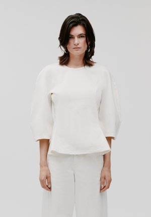 Witte, textuur blouse met een ronde hals, puffmouwen en een uitlopende zoom. Gekocht met bijpassende lichtgekleurde broek.