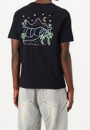 Camiseta negra de algodón con un gráfico colorido en la parte trasera que muestra montañas, una luna y palmeras en tonos pastel.