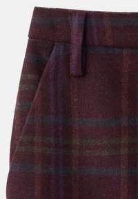 Wollen broeken in een donkere bordeauxkleur met een geruit patroon dat donkere blauwe en groene strepen bevat. Platte voorkant met een detail van de riemlus.