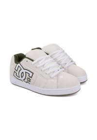 Białe zamszowe buty do skate'u z białymi sznurowadłami, zielonymi akcentami i dużym logo DC z boku. Posiadają płaską gumową podeszwę oraz przeszycia.