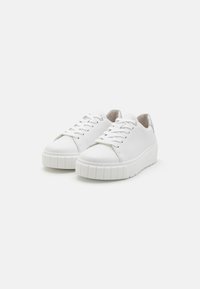Hvite sneakers laget av glatt skinn med rund tå, snøring og teksturert såle. Har en subtil metallisk aksent på hælen.